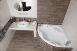 Rohová vaňa s obložením v dekore dreva, biele obklady a umývadlový pult s oválnym zrkadlom; pohľad zhora na vaňovú zónu