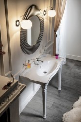 Retro ladený umývadlový stolík s dekoratívnym okrúhlym zrkadlom a dvoma nástennými lampami po stranách zrkadla