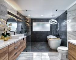 Priestranná kúpeľňa s vaňou aj sprchou oddelenou sklom, drevenými skrinkami pod umývadlom, kruhovým závesným svetlom a veľkým oknom s matným sklom.