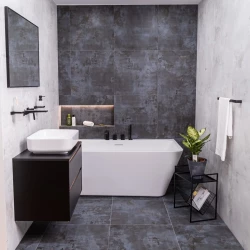 Kombinácia vane a umývadla: biela vaňa s čiernou batériou, tmavý šedý obklad s osvetlenou nikou na kozmetiku a závesná skrinka s umývadlom