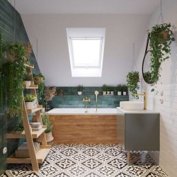 Podkrovná kúpeľňa s vaňou v drevenom obklade, zelenými obkladmi na stene, vzorovanou dlažbou a umývadlom so zlatou batériou; doplnené rastlinami