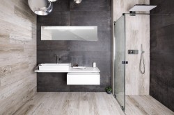 Moderná kúpeľňa s kombináciou šedých obkladov a dekoru svetlého dreva, závesnou skrinkou s umývadlom a čírym sprchovacím kútom s hornou sprchou