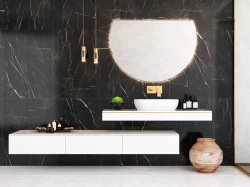 Luxusná umývadlová zóna na čiernom mramore: biele doskové umývadlo, zlatá batéria, veľké polkruhové podsvietené zrkadlo a závesné svetlá