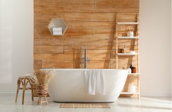 Voľne stojaca vaňa pred dreveným obkladom, drevená otvorená polica na kozmetiku, svetlá dlažba