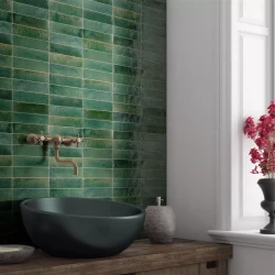 Detail umývadla: tmavé miskové umývadlo na drevenej doske, zelené „tehličkové“ obklady a nástenná batéria v retro štýle