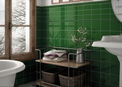 Vintage kúpeľňa s lesklými zelenými obkladmi, oknom v drevenom ráme, vaňou a drôteným regálom s košíkmi