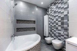 Kúpeľňa s rohovou vaňou, šedými a mozaikovými obkladmi; závesné WC a bidet
