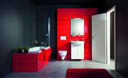 Kontrastná kúpeľňa s tmavými stenami, červeným obkladom vane a steny za umývadlom; závesné WC