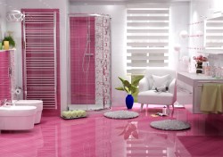 Výrazne ružová kúpeľňa s lesklou dlažbou, rohovým sprchovacím kútom, bielym kreslom a dvojicou umývadiel na dlhej skrinke