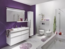 Bielo-fialová kúpeľňa s umývadlovou skrinkou, veľkým zrkadlom, závesným WC a bidetom; fialová akcentná stena a okrúhle kúpeľňové predložky