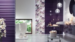 Luxusná kúpeľňa s tmavo fialovými lesklými obkladmi, kvetinovým panelom, závesnými sklenenými svietidlami a odkladacím vozíkom so sviečkami