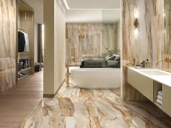 Moderná kúpeľňa s výrazným mramorovým dekorom v teplých tónoch, voľne stojacou vaňou a zlatou stojančekovou batériou pri vani