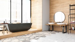 Interiér s voľne stojacou tmavou vaňou na drevenej podeste, umývadlami na dlhej drevenej lavici, okrúhlym zrkadlom a patchworkovou dlažbou