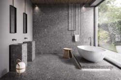 Minimalistický priestor so šedým kamenným dekorom, dvojicou hranatých umývadiel a voľne stojacou vaňou pri veľkom okne