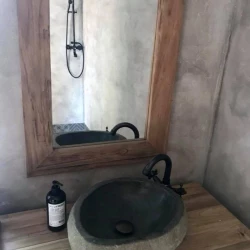 Kúpeľňa s kamenným umývadlom, dreveným rámom zrkadla a sprchou so stenami v betónovej stierke