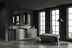 Luxusná tmavá kúpeľňa s dvojicou kamenných umývadiel, oválnymi zrkadlami a voľne stojacou vaňou pred vysokými oknami