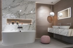 Elegantná kúpeľňa s bielym mramorovým obkladom, dvoma umývadlami na doske, voľne stojacou vaňou a jemne ružovým taburetom
